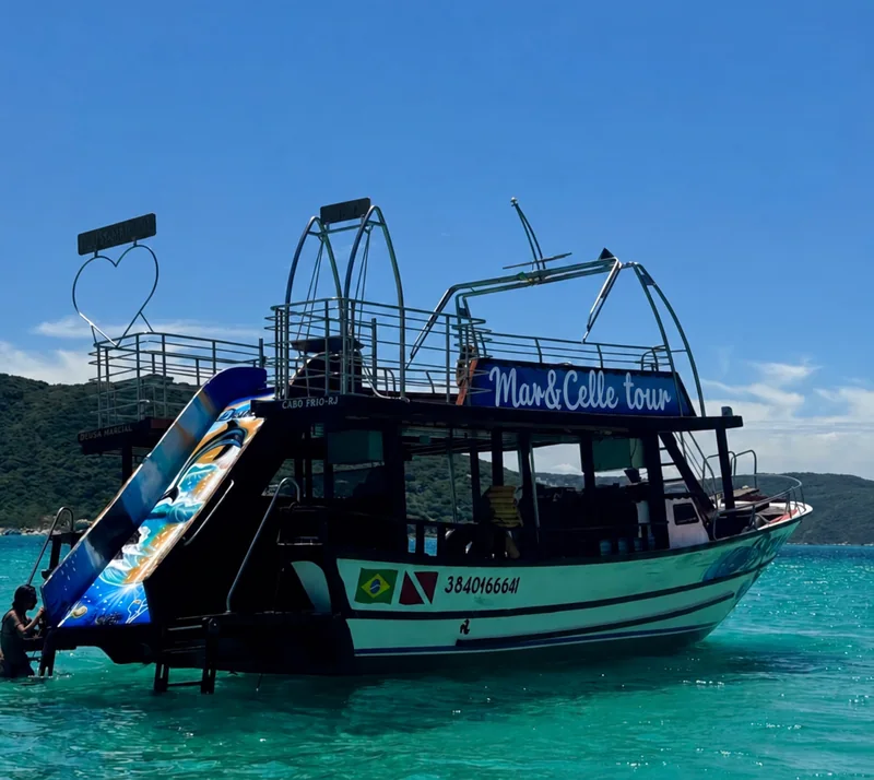 Barco da Mar&Celle Tour com toboágua ancorado em água turquesa em Arraial do Cabo