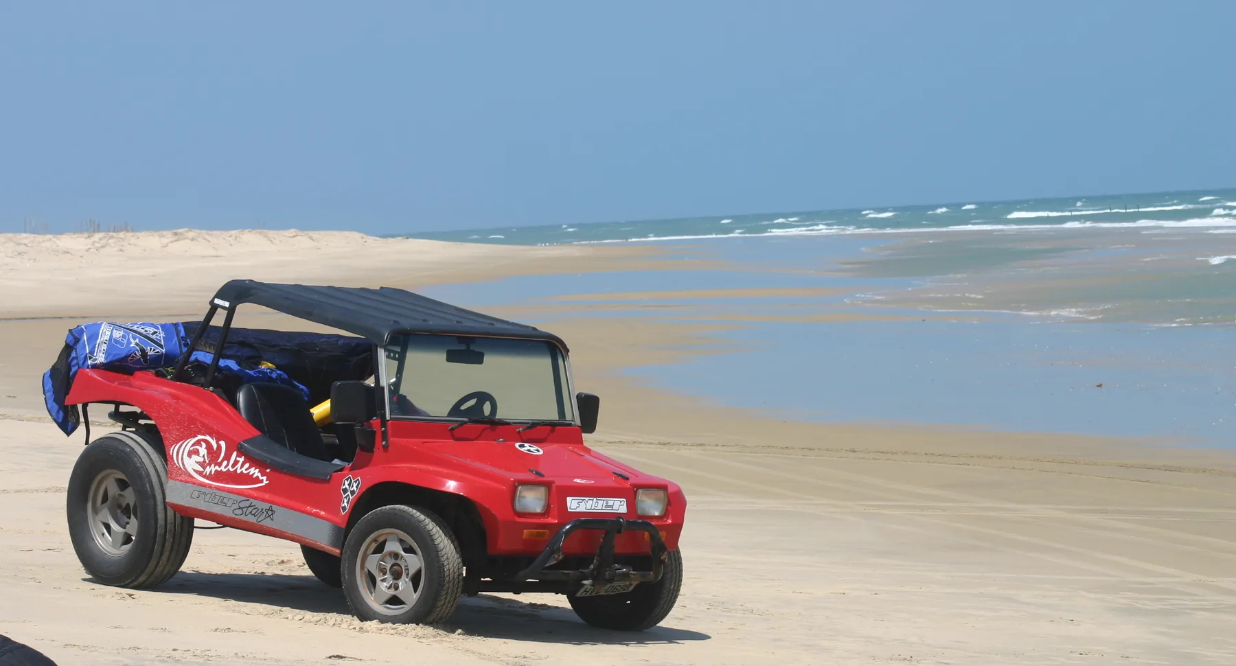 Buggy vermelho estacionado na areia da praia