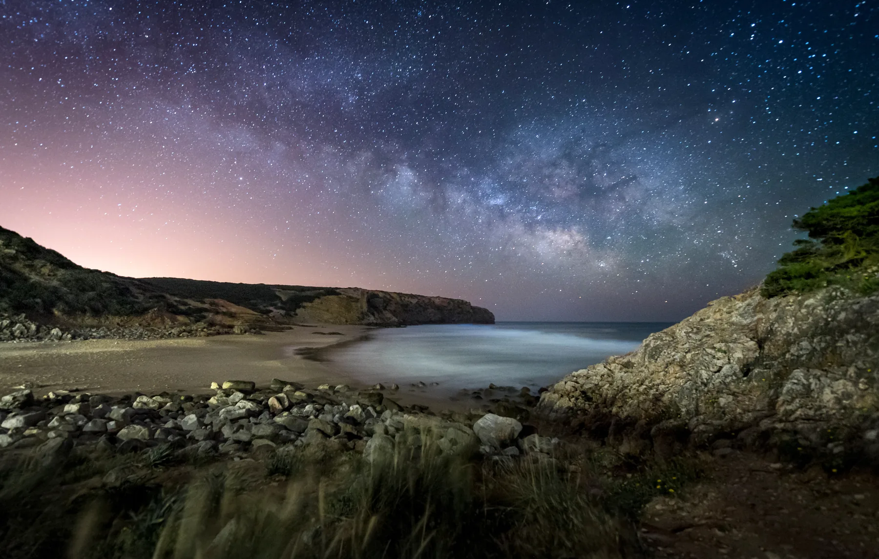 Via Láctea sobre uma praia à noite