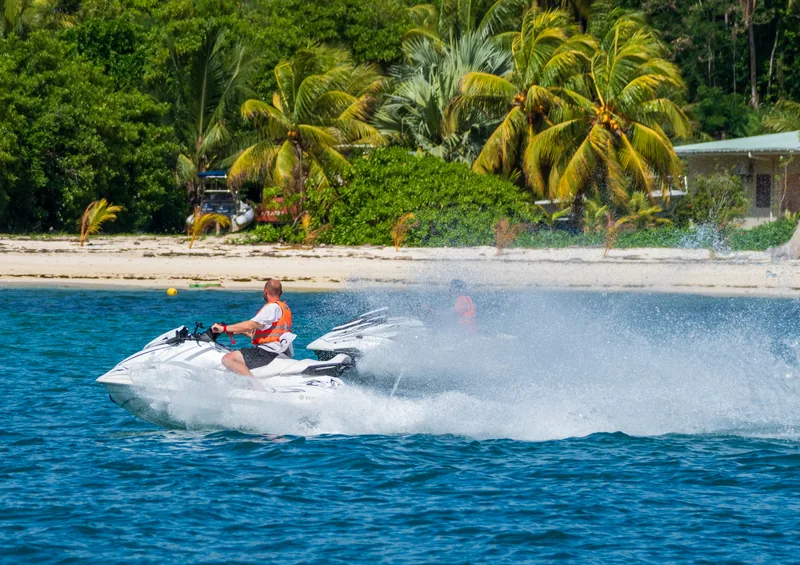 Jet ski acelerando em mar azul com coqueiros ao fundo