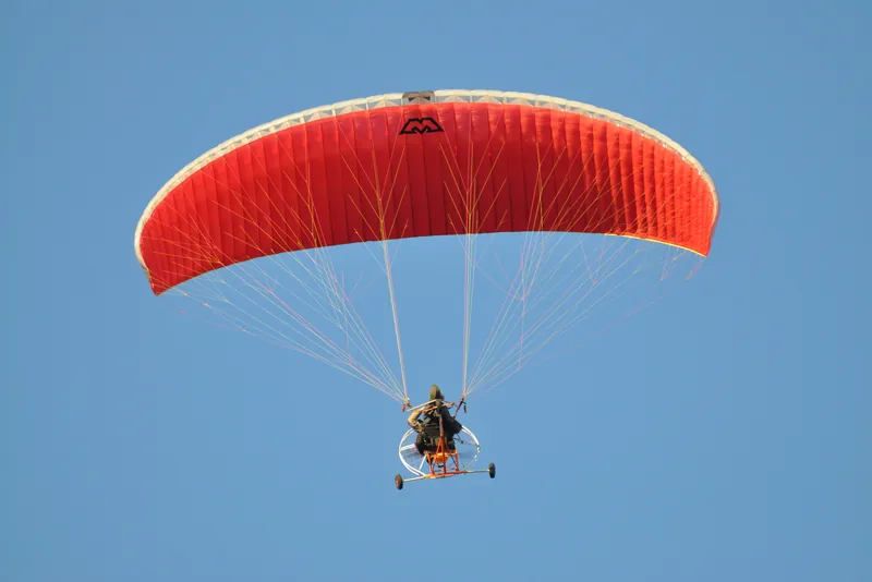 Paramotor com vela vermelha em voo