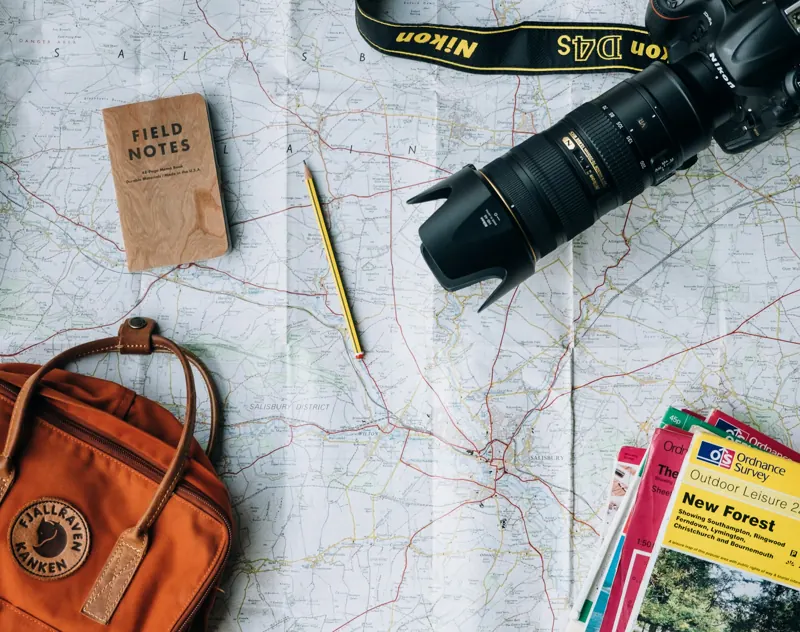 Mapa, caderno e câmera sobre a mesa para planejar viagem